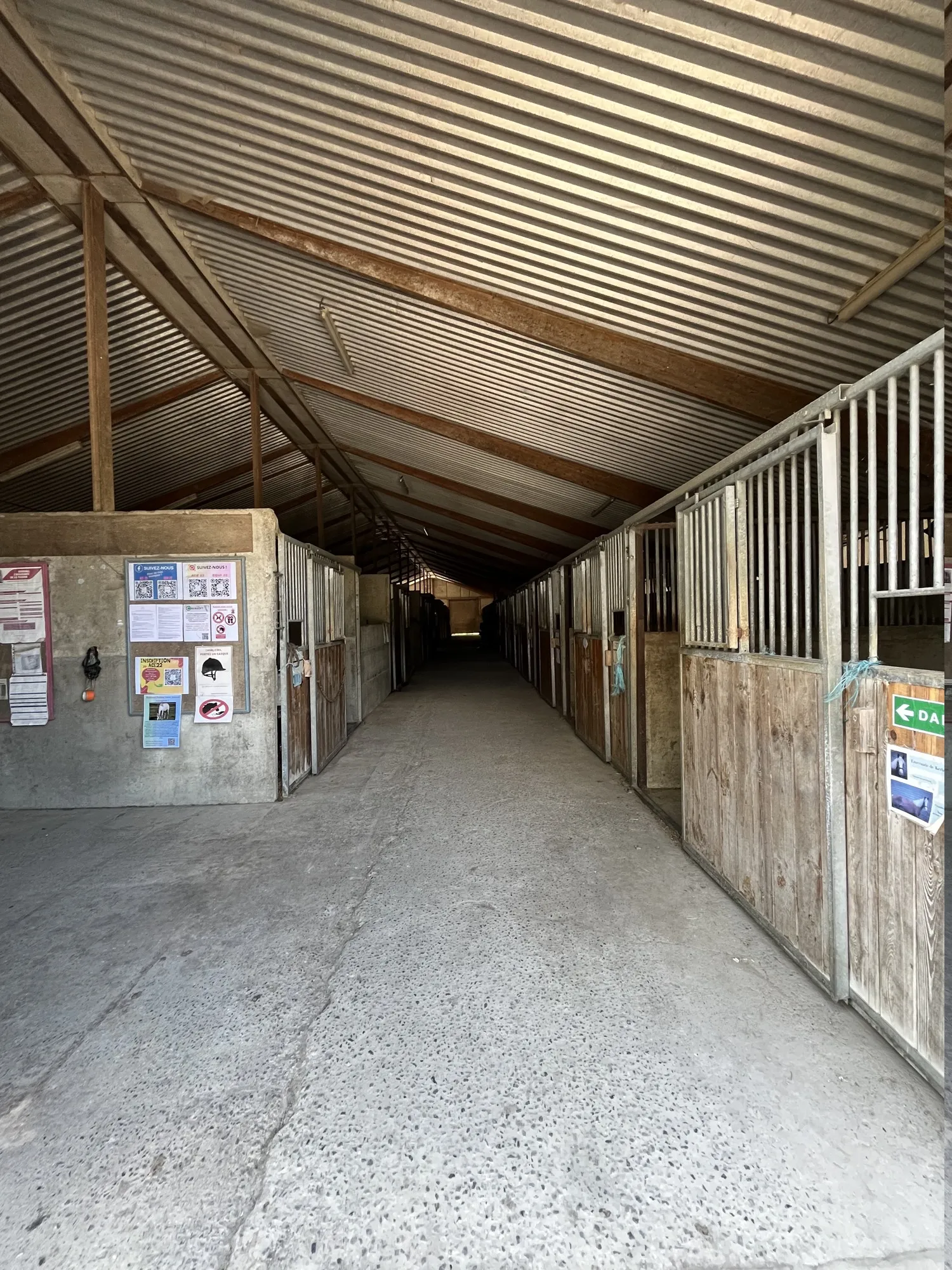 Couloir de l'écurie du centre équestre Équi 22 à Yffiniac, bordé de boxes individuels