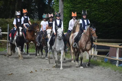 Enfants souriants sur des poneys dans le manège du centre équestre Equi 22