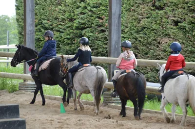 Enfants souriants sur des poneys dans le manège du centre équestre Equi 22